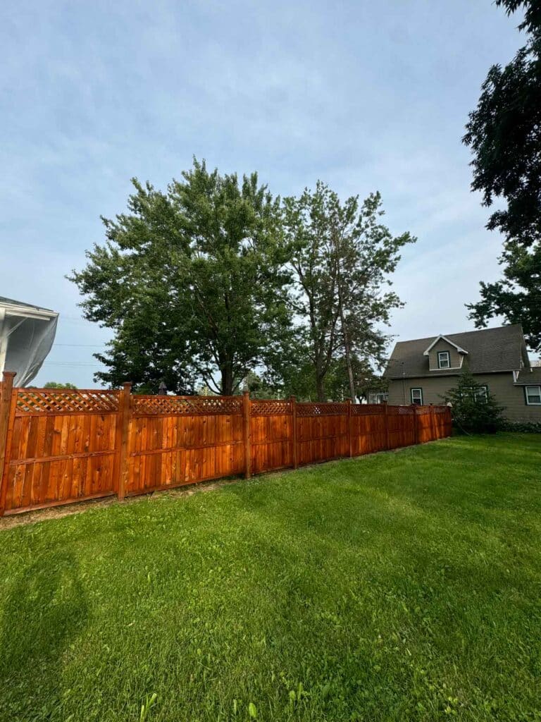 A Fence That Has Been Recently Stained In A Yard